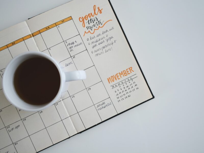 white ceramic mug with coffee on top of a planner