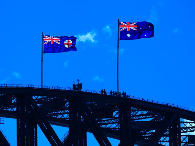 blue red and yellow flag on black metal bridge under blue sky during daytime