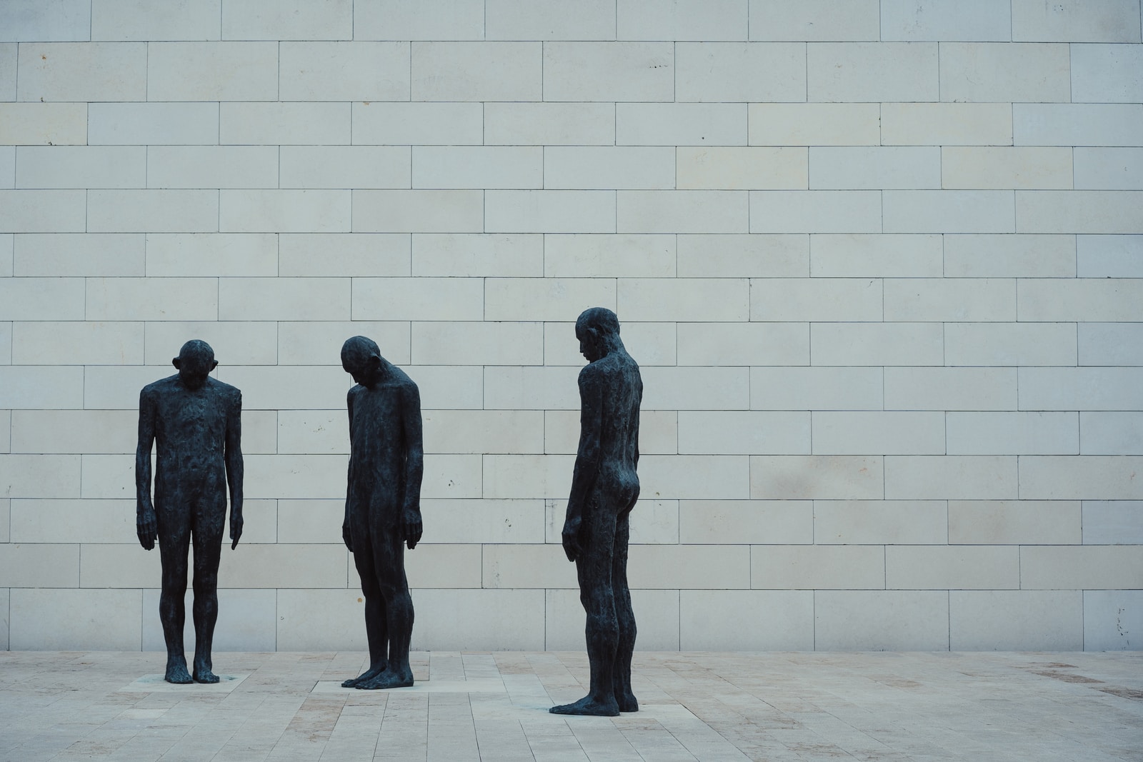 3 black statue standing on white concrete floor