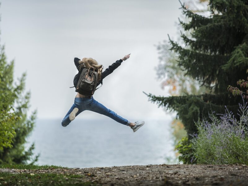 Woman Jumping Wearing Green Backpack