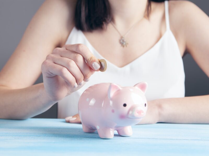 woman in white tank top holding pink pig figurine