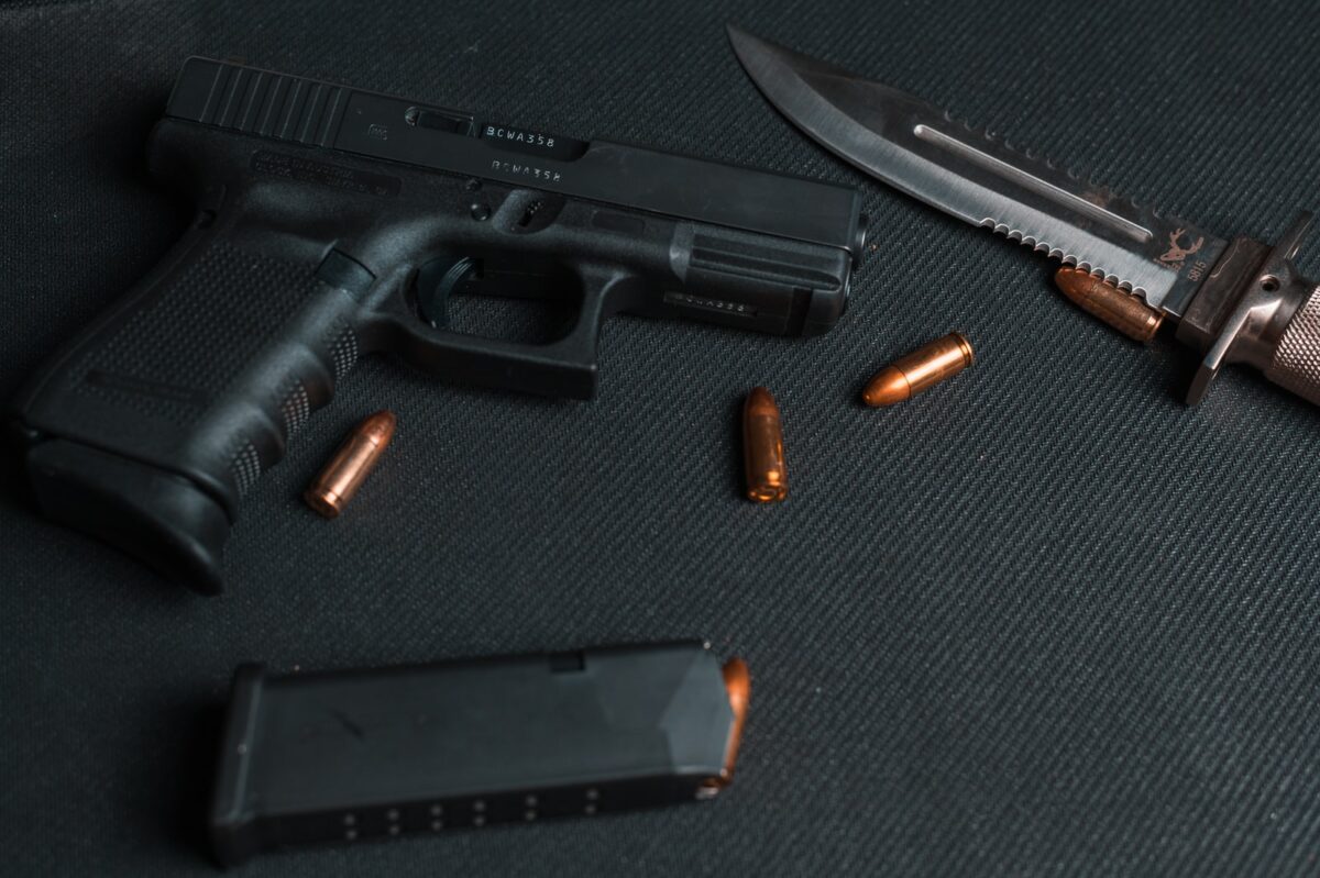 black semi automatic pistol beside brown and silver pocket knife