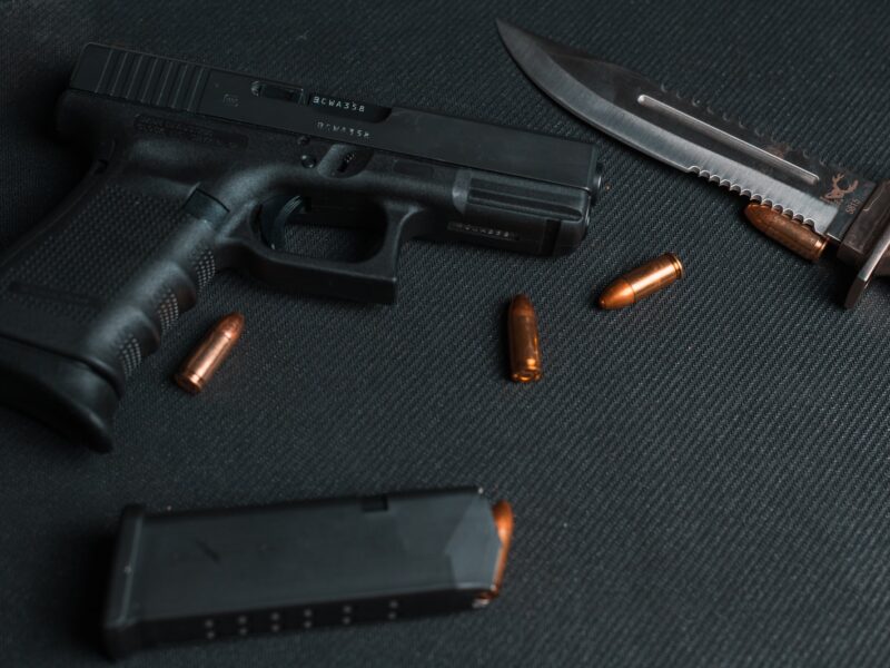 black semi automatic pistol beside brown and silver pocket knife