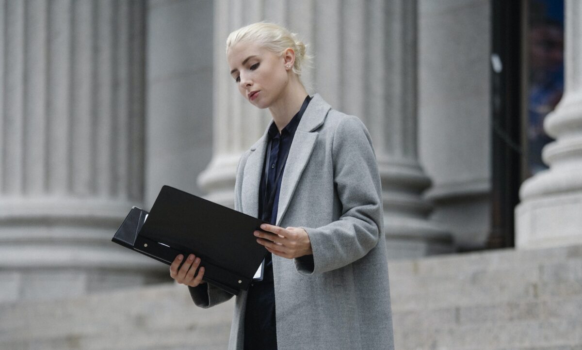 Contemplative businesswoman reading papers in folder outside building
