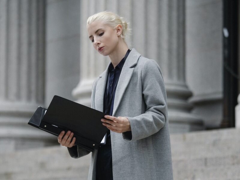 Contemplative businesswoman reading papers in folder outside building