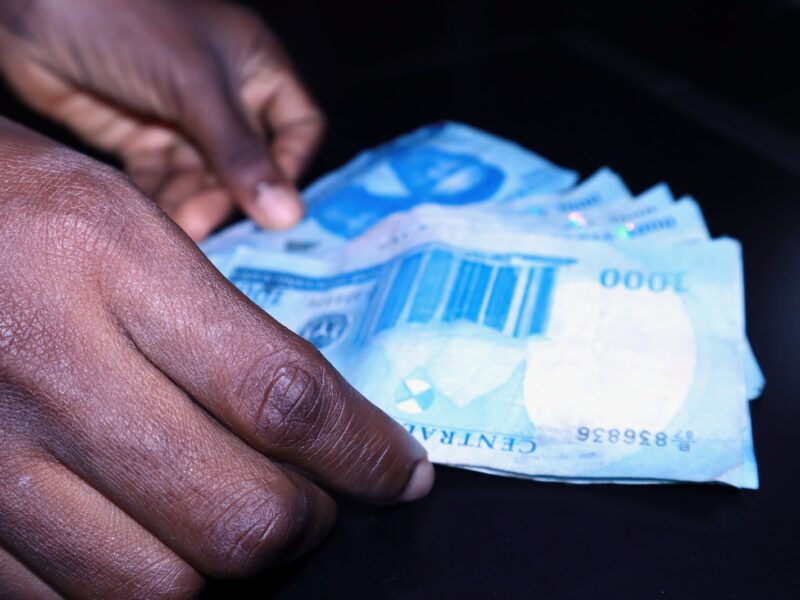 a person's hand reaching for a piece of paper money