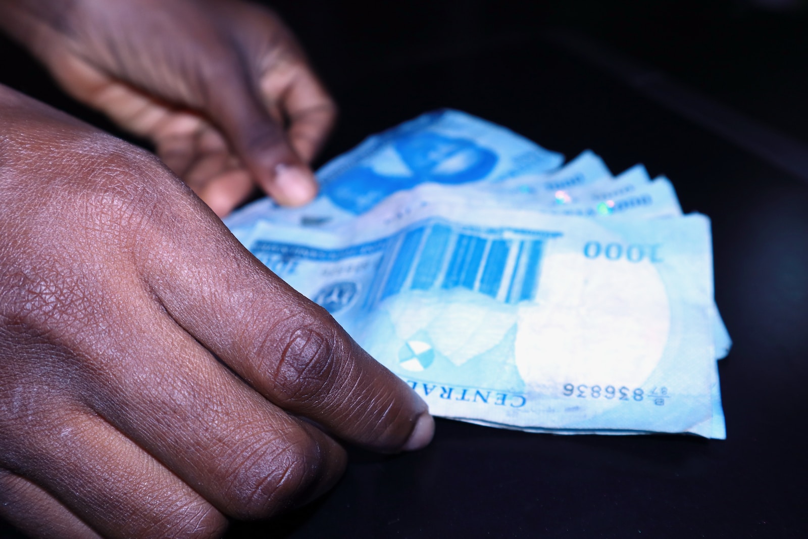 a person's hand reaching for a piece of paper money