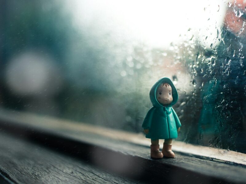kid wearing green jacket mini figure beside glass window