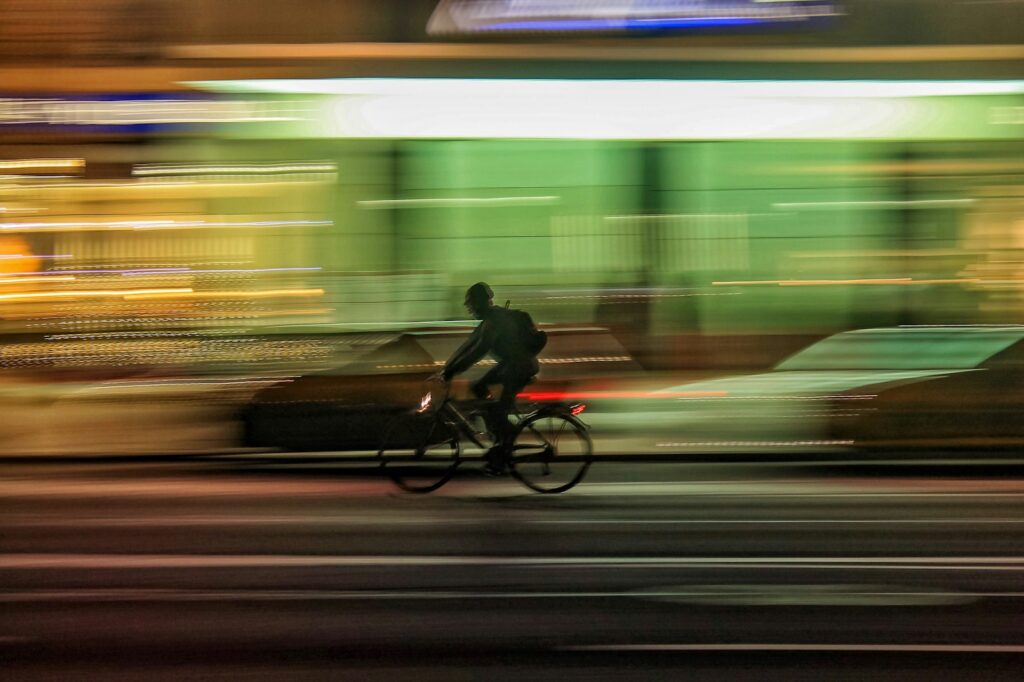 time lapse photo of person riding bicycle on road